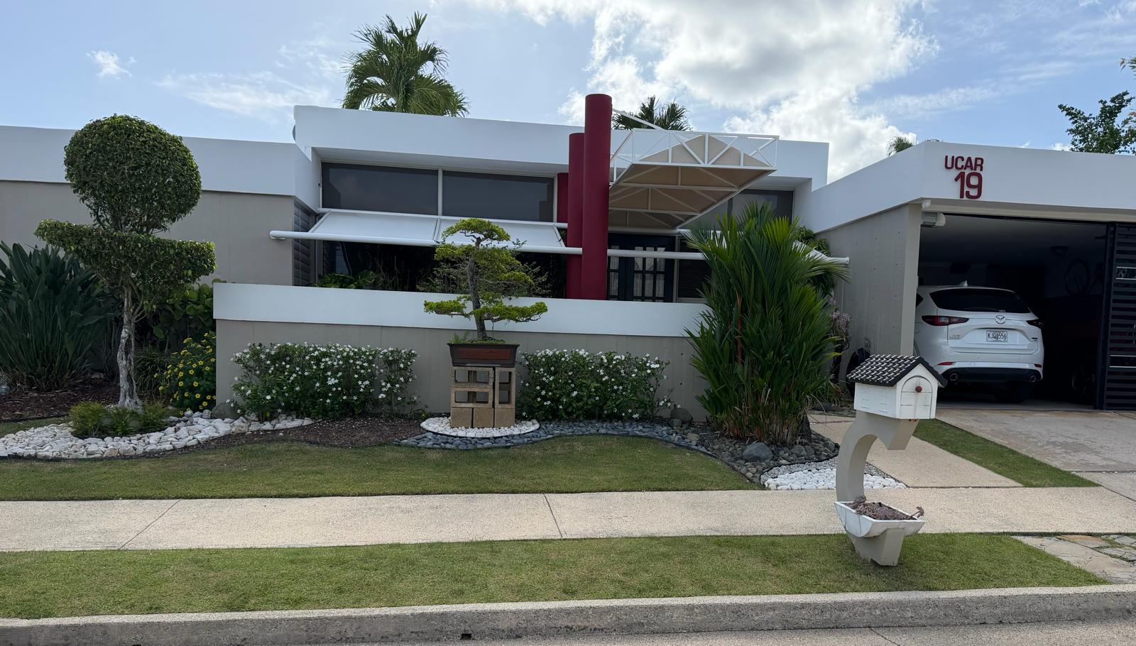 Fachada de residencia con jardín frontal y bonsái